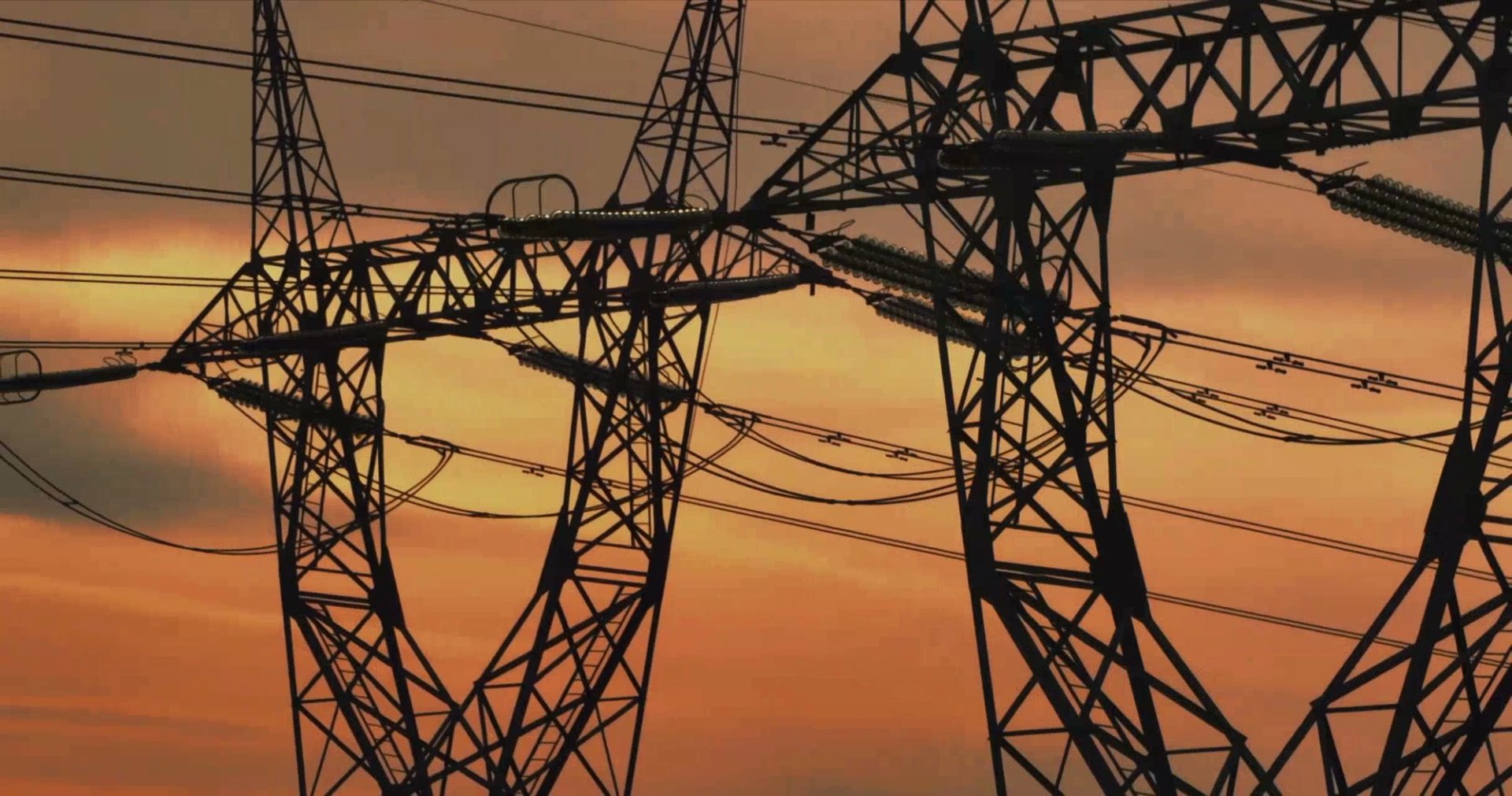 Electrical pylons silhouetted against a dusk sky